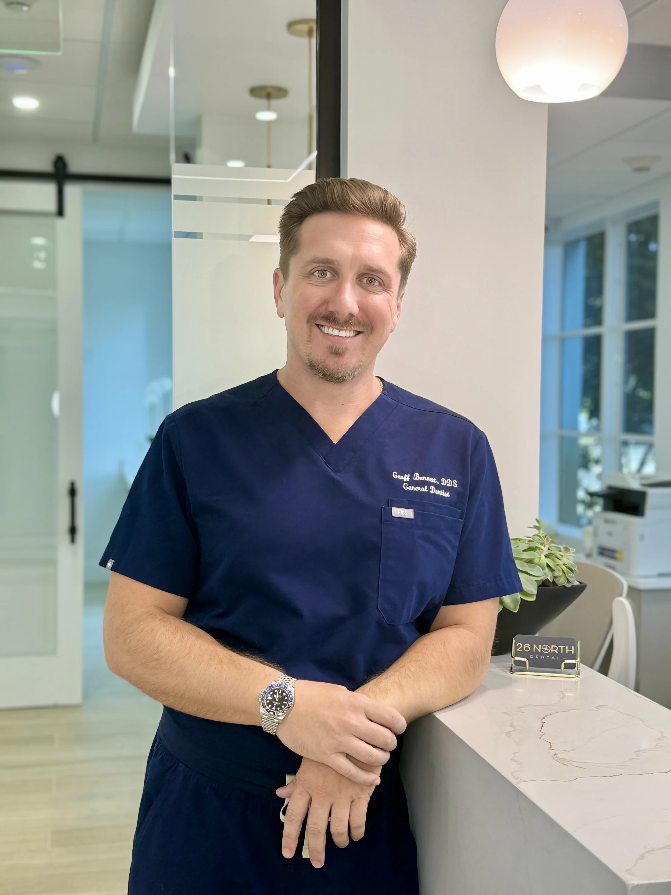 Dr. Geoffrey Bennett, DDS, wearing blue scrubs